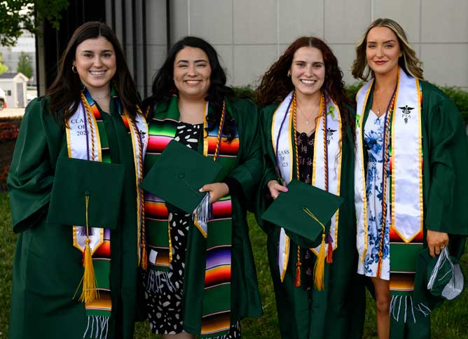 Four students with Honors stolls at graduation.