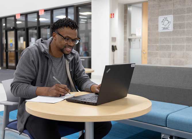 Student smiling and working on homework with someone over Zoom.